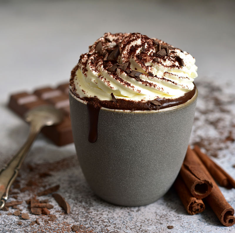 Hot Chocolate mit Sahnehaube und Schokopulver in einer kleinen Tasse