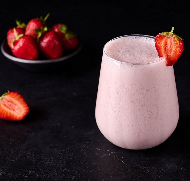 Ein Glas Strawberry Milkshake mit Erdbeeren in einem Schälchen