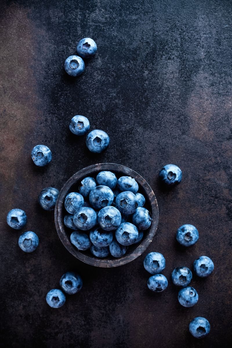 Einzelne Blaubeeren vor dunklem Hintergrund