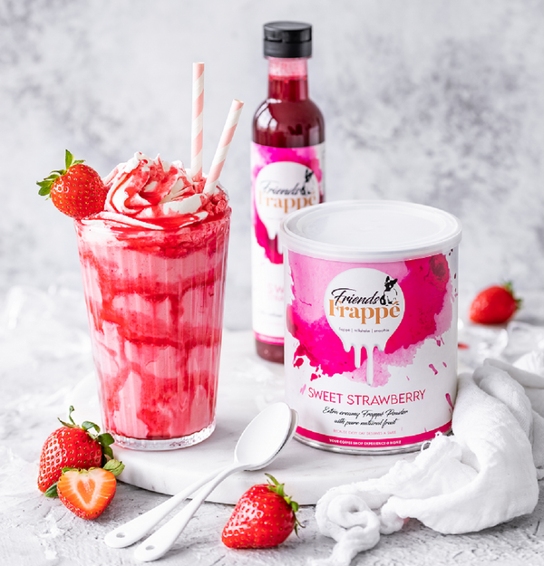 Komposition von Mix Pulver und Topping Créme Sweet Strawberry von Friends Frappé neben einem Strawberry Milchshake
