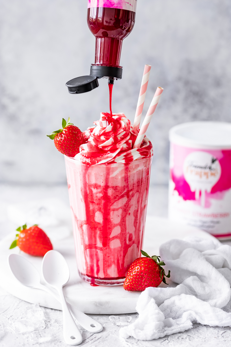 Topping Crème Sweet Strawberry wird über einen Sweet Strawberry Milchshake gegossen