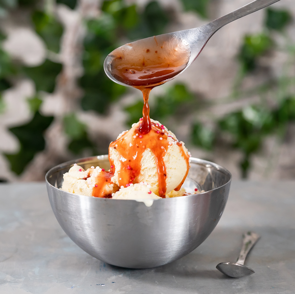 Topping Crème Feige Balsamico, die über einen Becher Vanilleeis gegossen wird