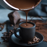Eingiessen einer cremigen Hot Chocolate in eine kleine Espresso Tasse